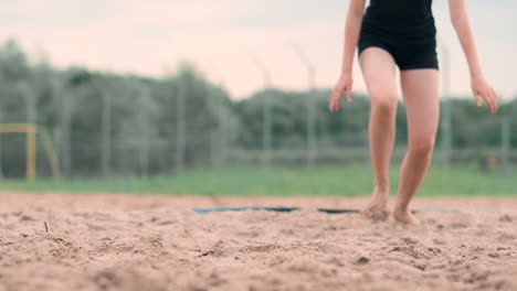 Young-female-athlete-dives-into-the-sand-and-saves-a-point-during-beach-volleyball-match.-Cheerful-Caucasian-girl-jumps-and-crashes-into-the-white-sand-during-a-beach-volley-tournament.